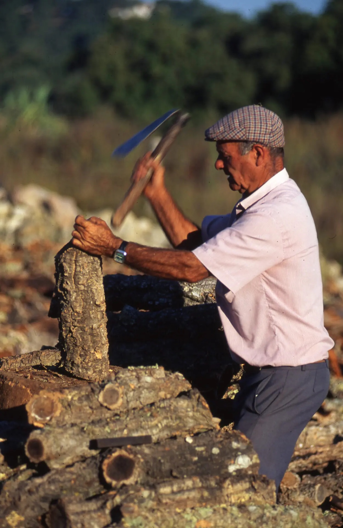 Trabalhador a trabalhar uma prancha de cortiça com um machado próprio