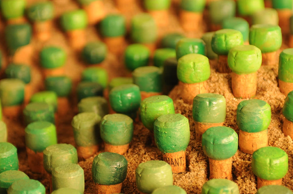 Rolhas de cortiça pintadas de verde, plantadas lado a lado como uma pequena floresta.