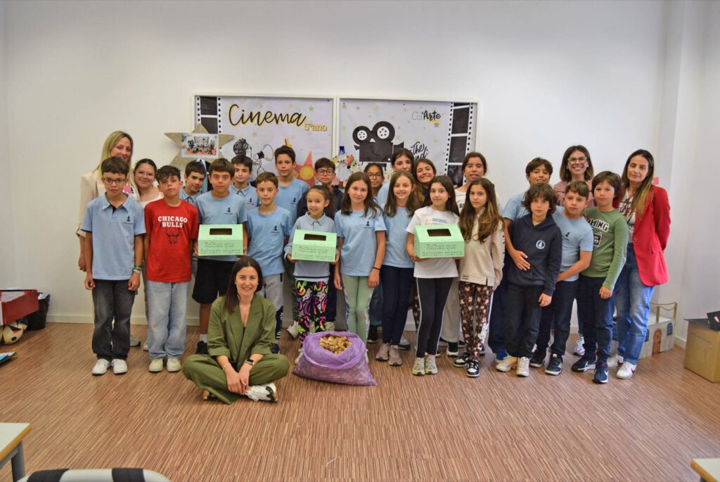 Turma de alunos e professoras numa sala de aula, três deles a segurar caixas verdes de recolha de rolhas