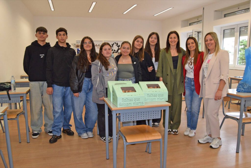 Grupo de estudantes e professoras numa sala de aula, com duas caixas verdes de recolha de rolhas numa mesa